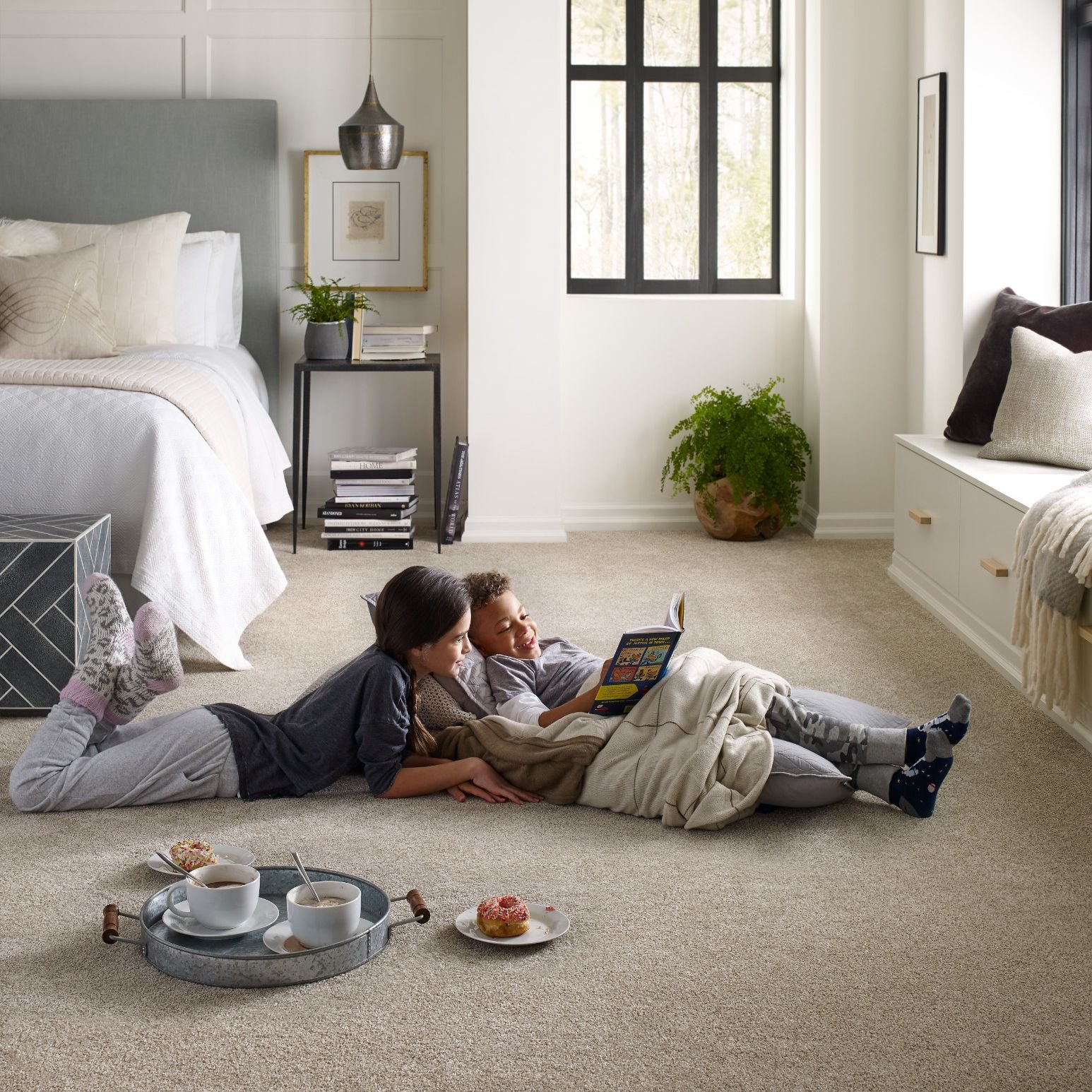 young boy and girl laying on carpet in bedroom reading a book